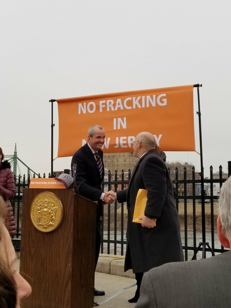 Governor Phil Murphy shakes hands with Mayor Ellis of Phillipsburg, with the Delaware River in the background.
